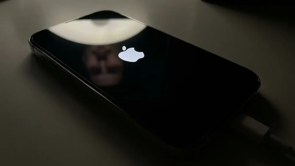 Why is My iPhone Stuck on Apple Logo? Reason & Quick Ways to Fix Close-up photograph of an iPhone 14 Pro screen displaying a stuck Apple logo on a black background.